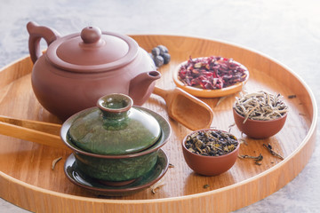 Traditional Chinese tea cup, ceramic teapot and tea ceremony attributes on a wooden tray