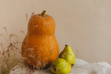 Pumpkin, pears and flowers lie on linen fabric. The concept of comfort, warmth and home. Autumn or fall abstract warm background. Flat lay, top view, copy space. Thanksgiving day concept.