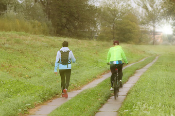 Two girls play sports in sunny morning`s weather. Cycling and walking under rain drops in sunny weather. Sport and healthy lifestyle. Taking care of your body and exercise. Journey to two.