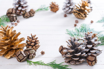 Christmas decoration background: pine and cypress cones with twigs on white wood table