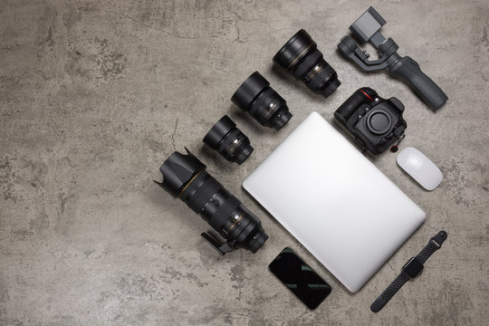 Photography equipment to travel on bare mortar background, DSLR camera,  Lenses, laptop, mouse, gimbal and smart watch