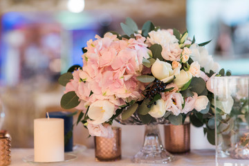 Composition from flowers - decoration of a table for guests. White candles in big glass vases