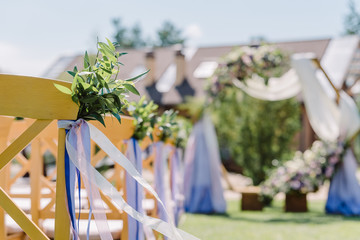 Wooden chairs at a wedding. The chairs decorated with buttonholes and tapes for guests