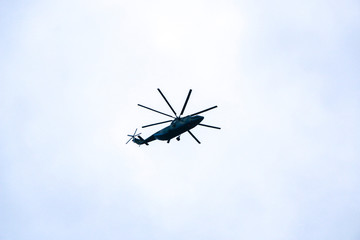 a large military helicopter hovers in the sky. A camouflaged helicopter flies at high speed.