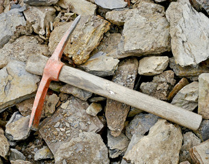 Pickaxe on stones to be used for the construction of a dry stone wall for agricultural use.