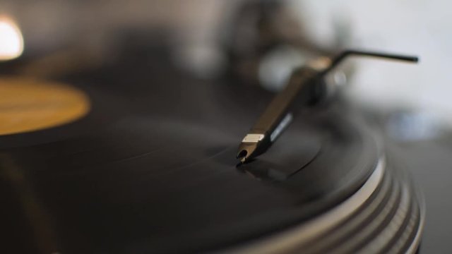 Listening to a vinyl record lp on a turntable at home needle closeup