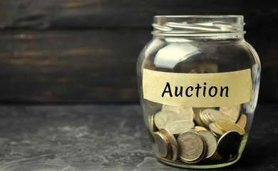 Glass jar with money and the inscription "Auction". Public sales, property of enterprises, bargaining. Organization of auction trade. Interbank auction loans
