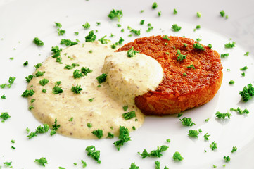carrot patty under sour cream mustard sauce decorated with parsley