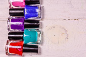Different nail polishes on a wooden table. Top view
