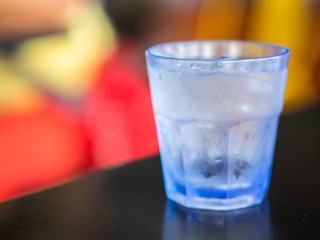 Closeup of plastic grass of cold water on black table and colorful color background.
