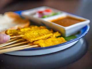 Closeup of Thai pork satay with peanut sauce and grilled bread.