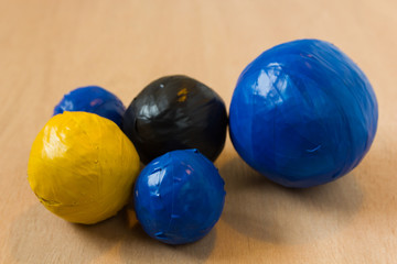 Fototapeta na wymiar colourful duct tape balls of blue, black and yellow in various sizes made by a child on school holidays