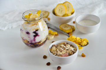 Breakfast in a jar: cereal, banana, fresh berries, granola, yogurt on a light background. The concept of healthy eating, high-carbon Breakfast.