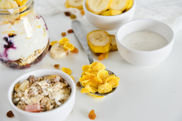 Breakfast in a jar: cereal, banana, fresh berries, granola, yogurt on a light background. The concept of healthy eating, high-carbon Breakfast.