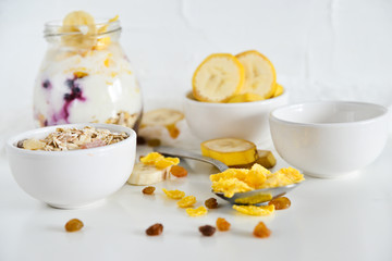 Breakfast in a jar: cereal, banana, fresh berries, granola, yogurt on a light background. The concept of healthy eating, high-carbon Breakfast.