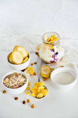 Obraz na płótnie Canvas Breakfast in a jar: cornflakes, banana, fresh berries, granola, yogurt on a light background. The concept of healthy eating, high-carbon Breakfast.