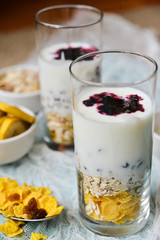 Healthy Breakfast: homemade granola, banana, fresh berries, yogurt in glass cups on light textile background. The concept of healthy eating, high-carbon Breakfast.