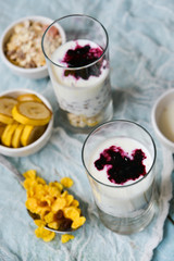 Healthy Breakfast: homemade granola, banana, fresh berries, yogurt in glass cups on light textile background. The concept of healthy eating, high-carbon Breakfast.