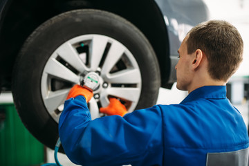 Mechanic unscrews the wheel, tire service