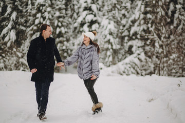 Fototapeta na wymiar Stylish couple in love having fun in snowy mountains. Happy family playing in snow and smiling in winter mountains and forest. Holiday getaway together. Romantic moments