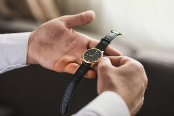 Fototapeta premium businessman checking time on his wrist watch, man putting clock on hand,groom getting ready in the morning before wedding ceremony