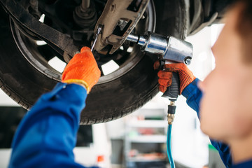 Technician with a wrench repair car suspension