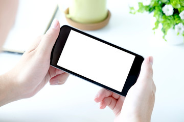 Man with modern mobile phone in hands touching on a blank screen. Blurred office interior on a background.