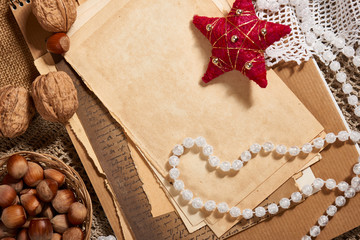 Old paper and christmas decoration as background, beads, gifts, nuts and other stuff on sackcloth. Empty space for text, new year theme.