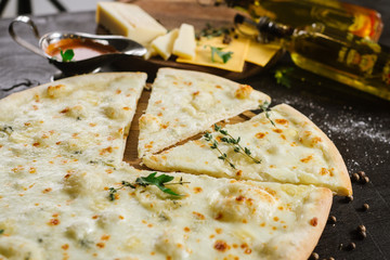 A pizza with different kind of cheese on black background
