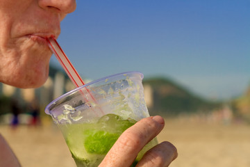 Woman drinking caipirinha on Copacabana beach (Rio de Janeiro, Brazil)