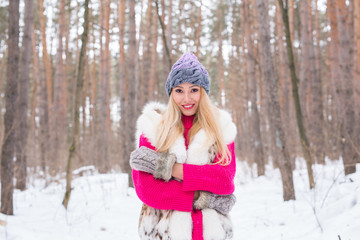 Fototapeta premium Nature, fashion and people concept - Young attractive blond woman posing in the winter park.