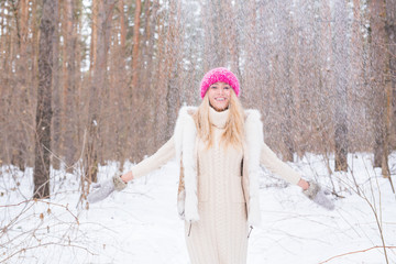 Fototapeta premium Winter, walks and people concept - young blond woman walking in the winter forest and throwing the snow up