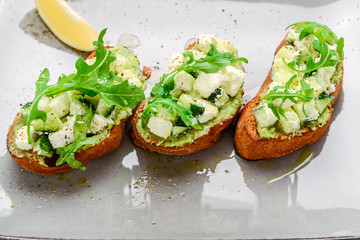 Tasty savory Italian appetizers, or bruschetta, on slices of toasted baguette garnished with basil