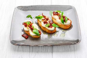 Tasty savory Italian appetizers, or bruschetta, on slices of toasted baguette garnished with basil