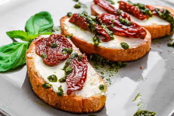 Tasty savory Italian appetizers, or bruschetta, on slices of toasted baguette garnished with basil