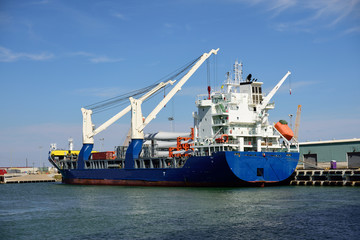 Wide view of a cargo freighter at dock unloading 36 meter wind energy turbine blades at the Port of Corpus Christi, Texas