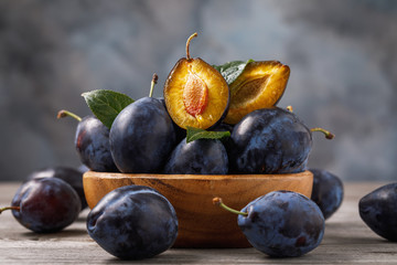 Full plate of ripe prune fruits on a wooden table, close-up