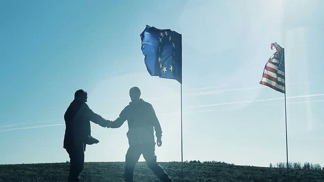 Handshake on the background of the flags of America and the European Union