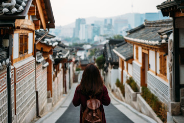 Young woman traveler traveling into Bukchon Hanok Village at Seoul city, South Korea. Bukchon Hanok Village is home to hundreds of traditional houses.