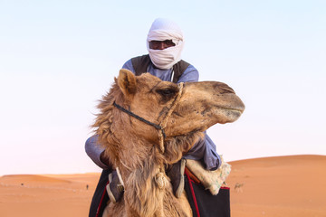 A Sudani shepherd  man riding a camel in Dahna desert - the eastern side of the city of Riyadh.