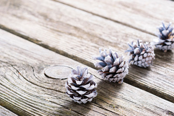 white painted pine cones Christmas decoration on old rustic wood table background