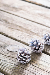three white painted pine cones Christmas decoration on old rustic wooden table background