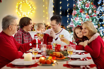 Family with kids having Christmas dinner at tree