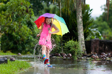 Kid with umbrella playing in summer rain.