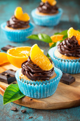 Orange Cupcakes with Chocolate Cream and Fresh Tangerines close-up on a blue stone or concrete...