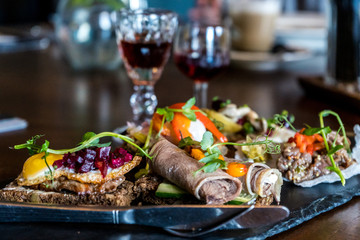 Finger food sandwiches of Russian fusion cousin with various toppings accompanied by two shots of flavored distilled spirit drink