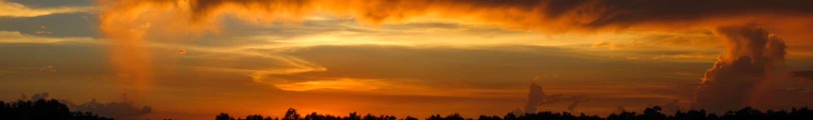 Amber rain clouds on horizon after sunset panorama