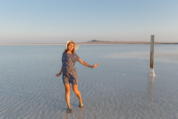 happy smiling girl enjoying the sunset, dancing in water of salt lake Bascunchak