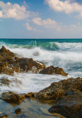 Beautiful Greek beach with big waves and rocks during cloudy sunset with long exposure.