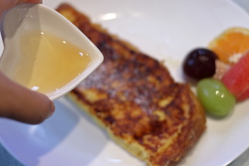 フレンチトーストに蜂蜜をかける女性	